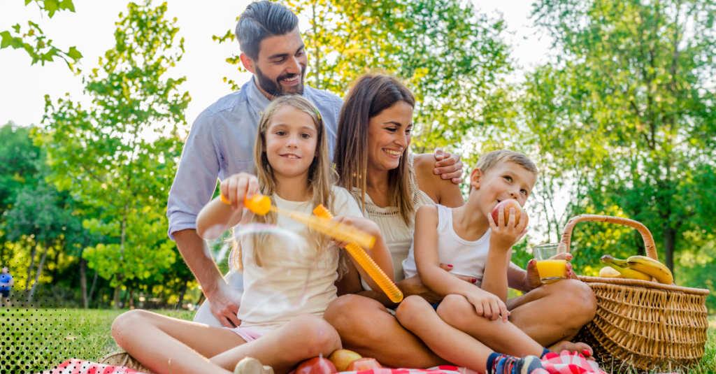 Happy family enjoying a sunny outdoor picnic, symbolizing fun fall activities and creating lasting memories together.
