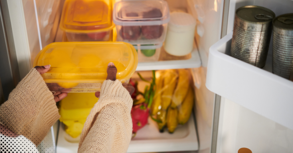 Person placing a food container inside a refrigerator.